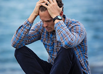 A man who has lost hope, sitting with his hands on his head feeling defeated