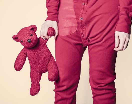 Adult in kids pajamas holding their teddy bear
