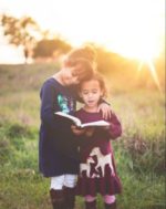 children reading together in a field