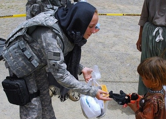 female soldier given toy to children in refugee camp